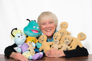 Jessica Shields Flowers smiling, surrounded by a group of plush toy characters